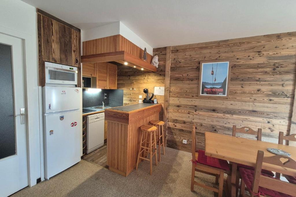 Il comprend une cuisine dotée d'un réfrigérateur blanc et d'un mur en bois. dans l'établissement Superbe appartement au pied des pistes -Le chamois, à Les Déserts