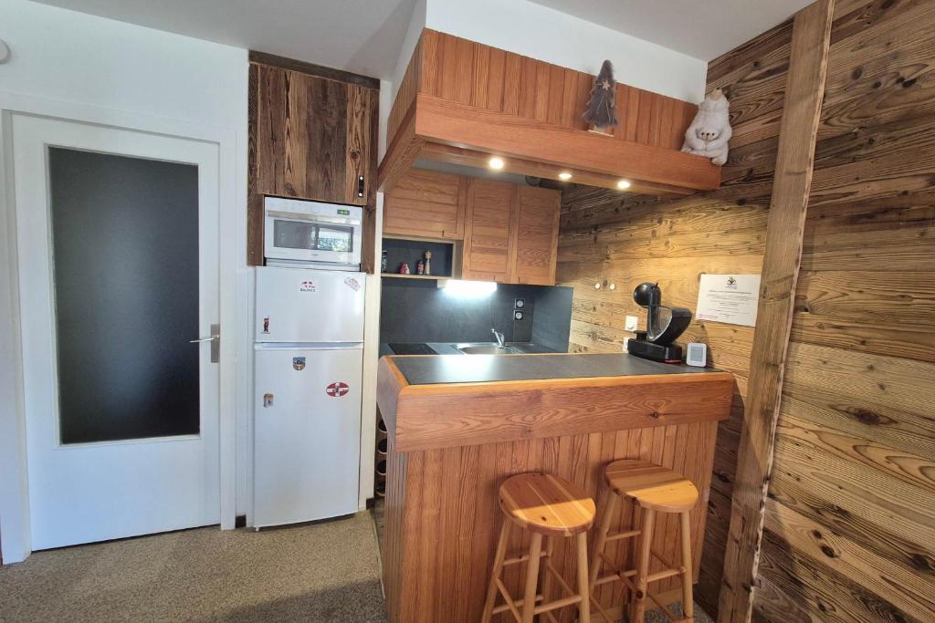 La cuisine est équipée d'un réfrigérateur blanc et de placards en bois. dans l'établissement Superbe appartement au pied des pistes -Le chamois, à Les Déserts 11 autres photos