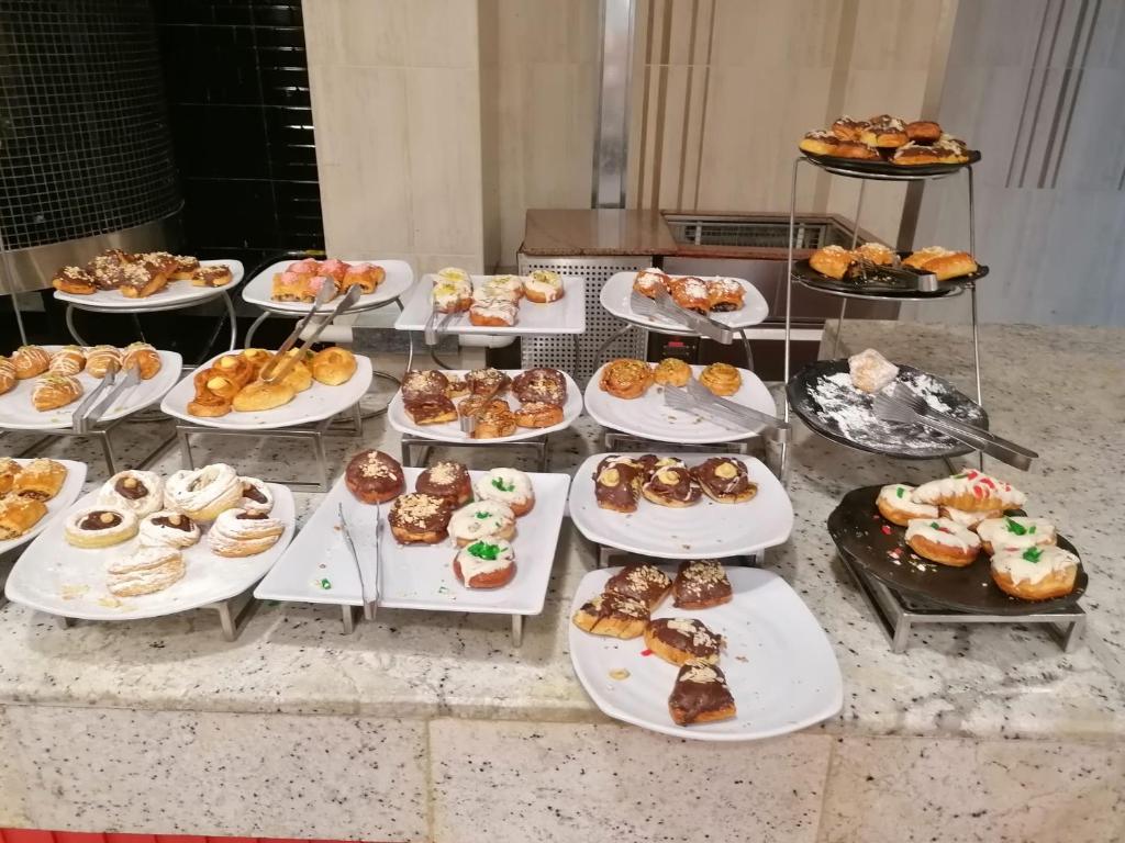 une table remplie de différents types de pâtisseries sur les assiettes dans l'établissement RESORT VILLAGE AQUA MARINA FAMILY - Daily Rooms Tidying - CocktailsBar- Pet Friendly - with Hypermarket - Delivery Restaurant-Pizzeria - Room Breakfast with supplement - Ultra Fast Wi-Fi - Play Area for children - Olympic Swimming Pool - Parking, à Caorle