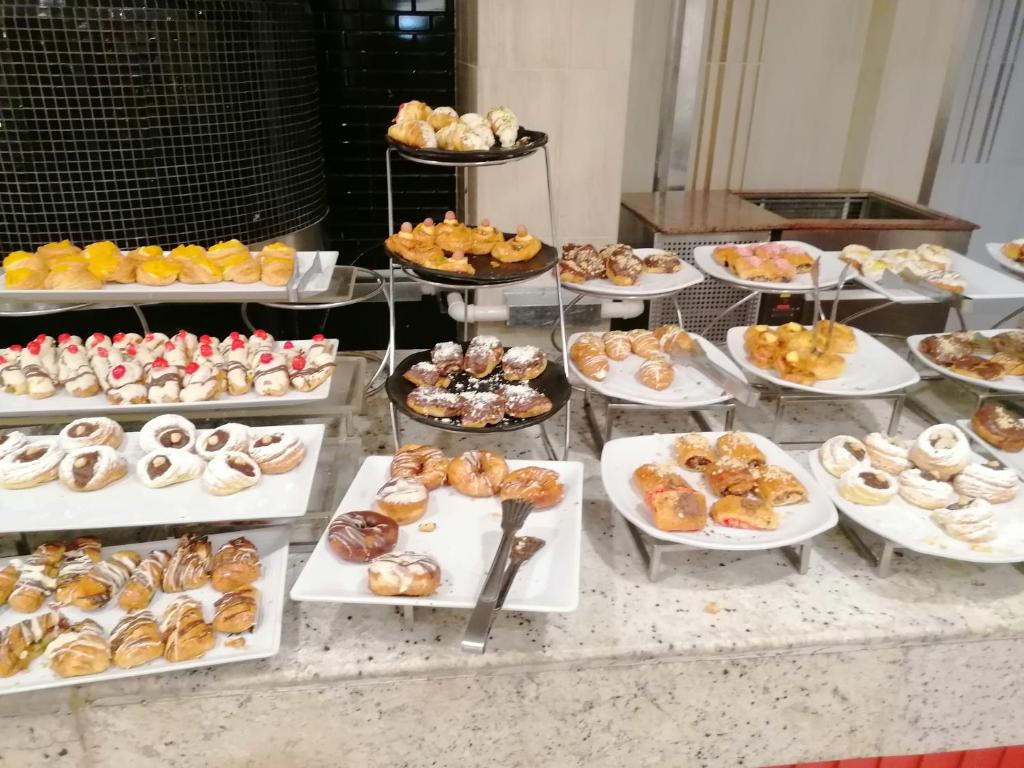 un buffet avec de nombreux types différents de beignets sur des assiettes dans l'établissement RESORT VILLAGE AQUA MARINA FAMILY - Daily Rooms Tidying - CocktailsBar- Pet Friendly - with Hypermarket - Delivery Restaurant-Pizzeria - Room Breakfast with supplement - Ultra Fast Wi-Fi - Play Area for children - Olympic Swimming Pool - Parking, à Caorle