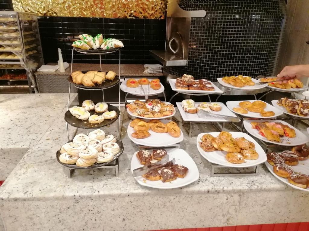 - une grappe de différents types de pâtisseries sur des assiettes sur un comptoir dans l'établissement RESORT VILLAGE AQUA MARINA FAMILY - Daily Rooms Tidying - CocktailsBar- Pet Friendly - with Hypermarket - Delivery Restaurant-Pizzeria - Room Breakfast with supplement - Ultra Fast Wi-Fi - Play Area for children - Olympic Swimming Pool - Parking, à Caorle