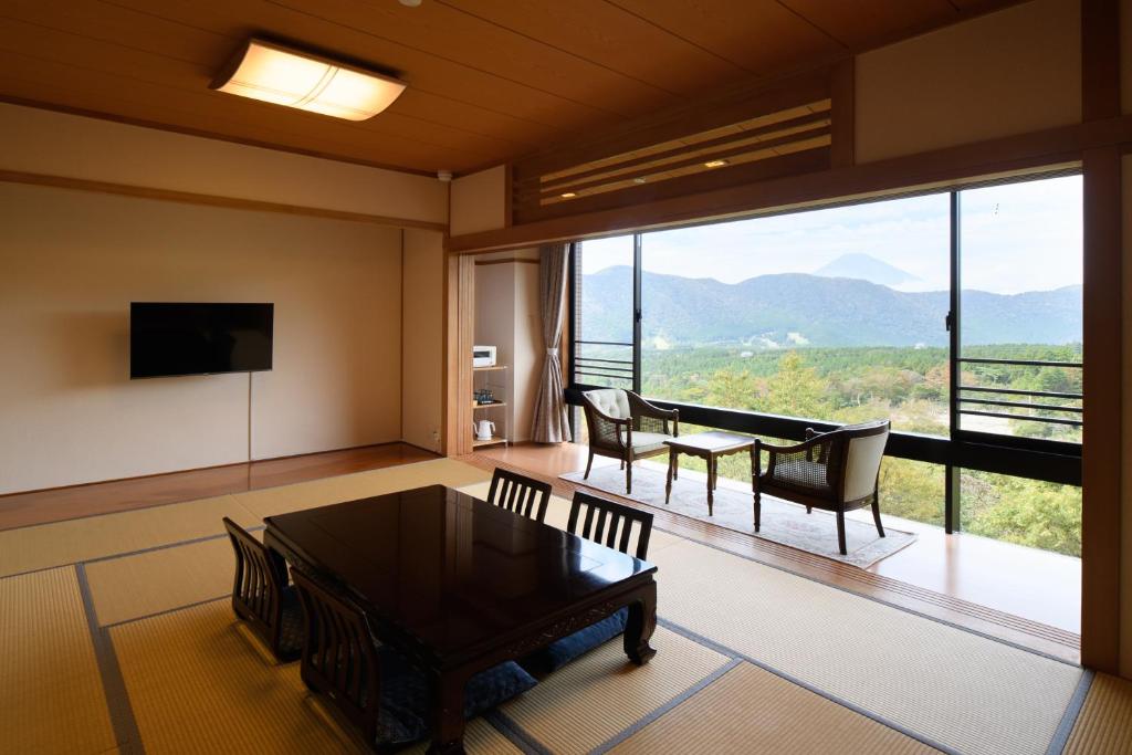 - un salon avec une table, des chaises et une grande fenêtre dans l'établissement Hakone Ashinoko Bikeikan 箱根芦ノ湖 美景館, à Hakone