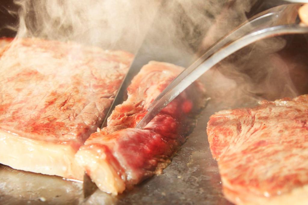 une spatule cuisant de la viande sur un gril dans l'établissement Beppu Fuga, à Beppu