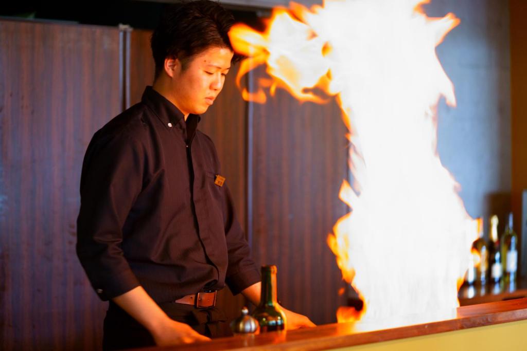 un homme debout au bar avec une bouteille de vin dans l'établissement Beppu Fuga, à Beppu