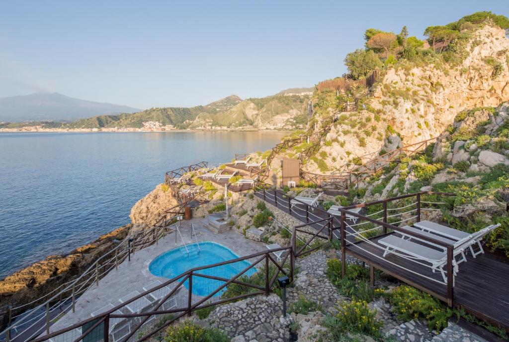 une piscine sur une falaise au bord de l'eau dans l'établissement UNA Hotels Capotaormina, à Taormine