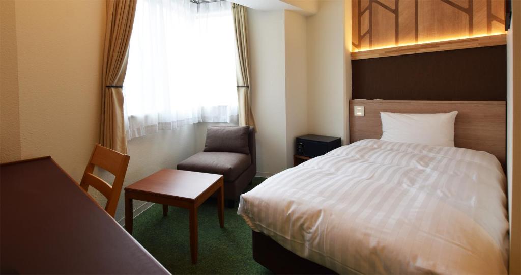 une chambre d'hôtel avec un lit, une chaise et une fenêtre dans l'établissement adex Inn, à Noboribetsu