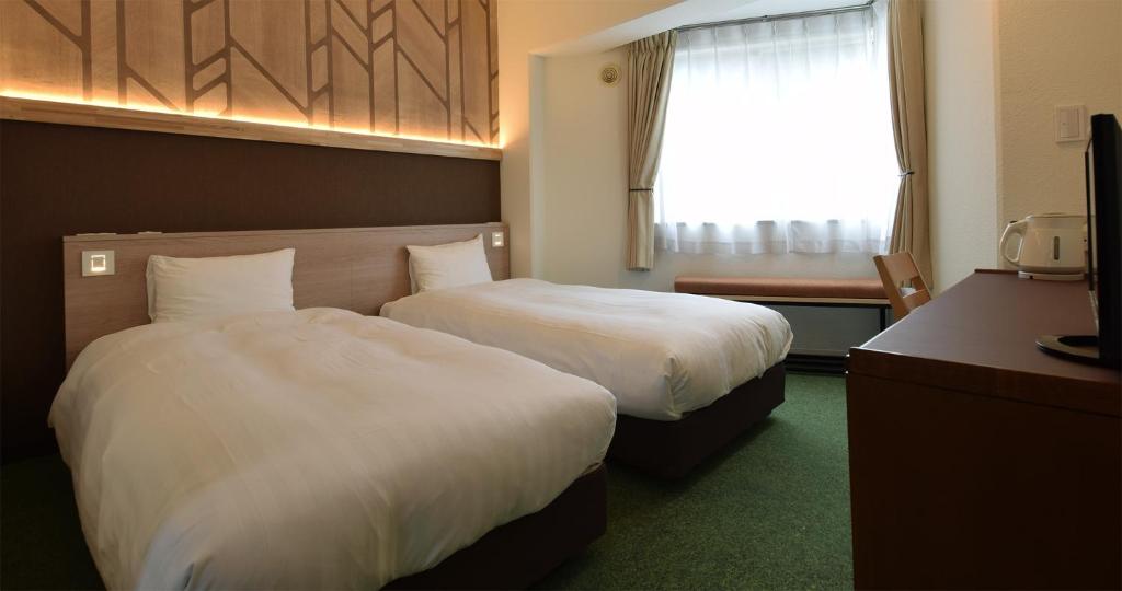 une chambre d'hôtel avec deux lits et une fenêtre dans l'établissement adex Inn, à Noboribetsu 9 autres photos