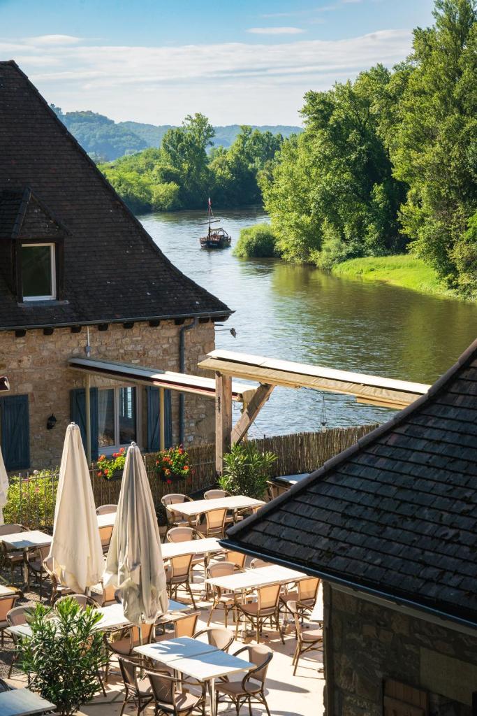 un patio avec des tables et des parasols à côté d'une rivière dans l'établissement Camping Le Sequoia, à Payrac