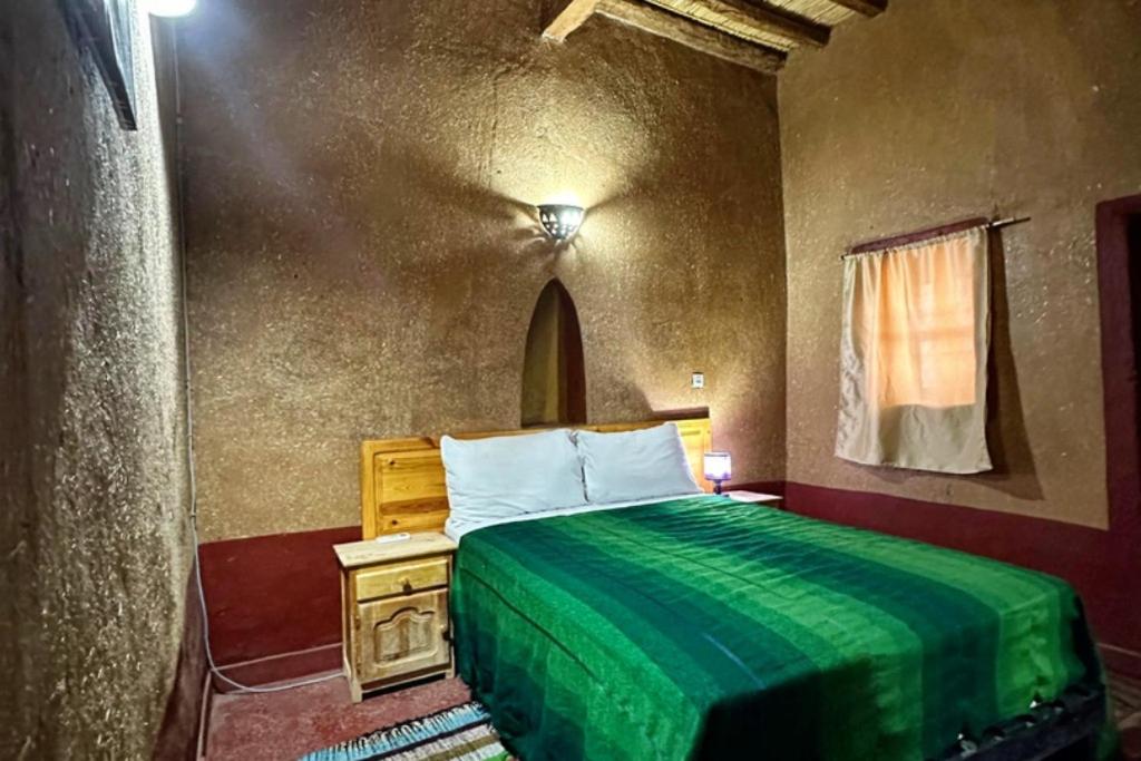 une chambre avec un lit avec une couverture verte dans l'établissement Riad Dar Zaouia, à Zagora