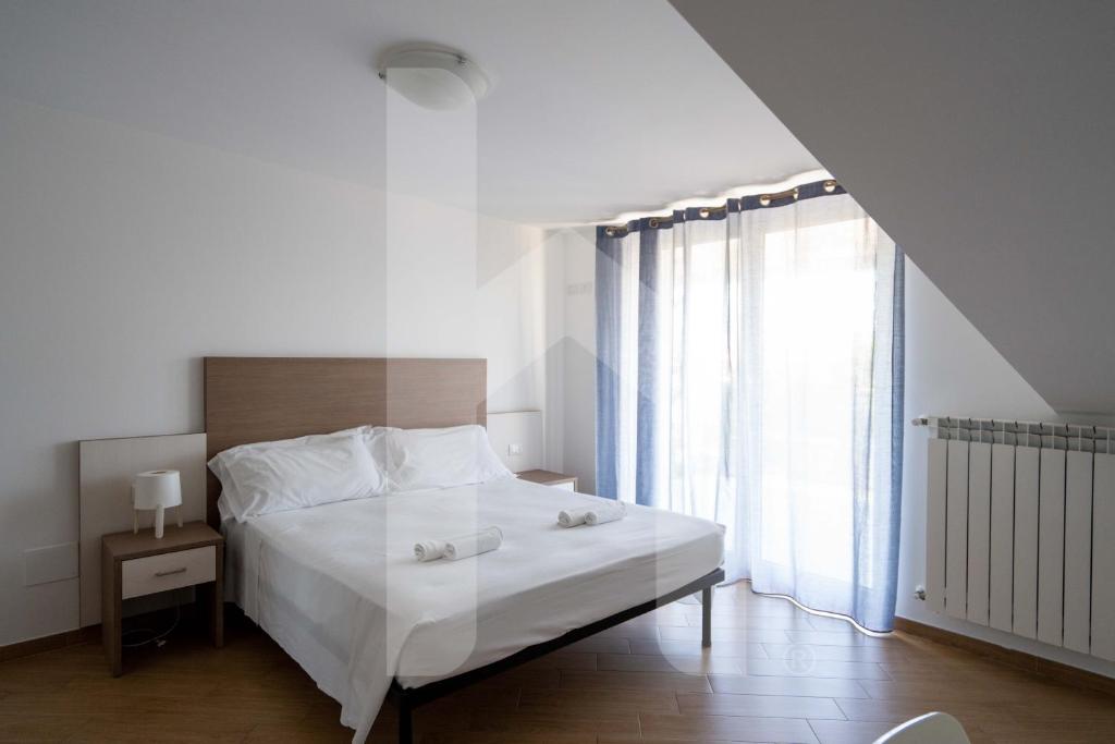 une chambre avec un lit avec des draps blancs et une fenêtre dans l'établissement Homiday - Residence K2, à Pineto