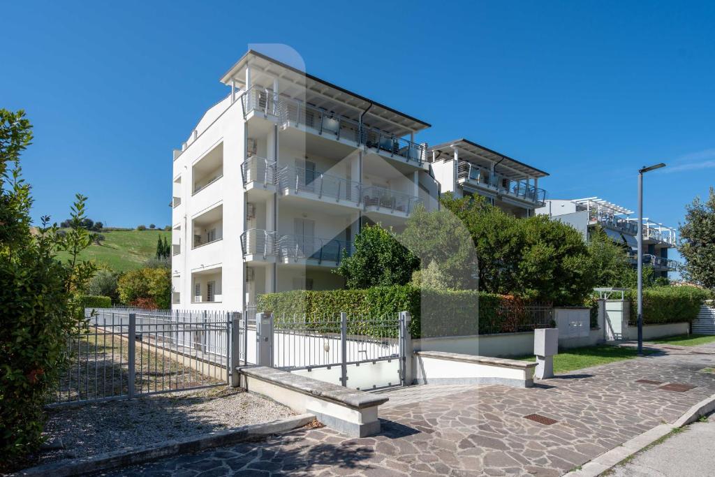 un bâtiment blanc avec une clôture devant dans l'établissement Homiday - Residence K2, à Pineto