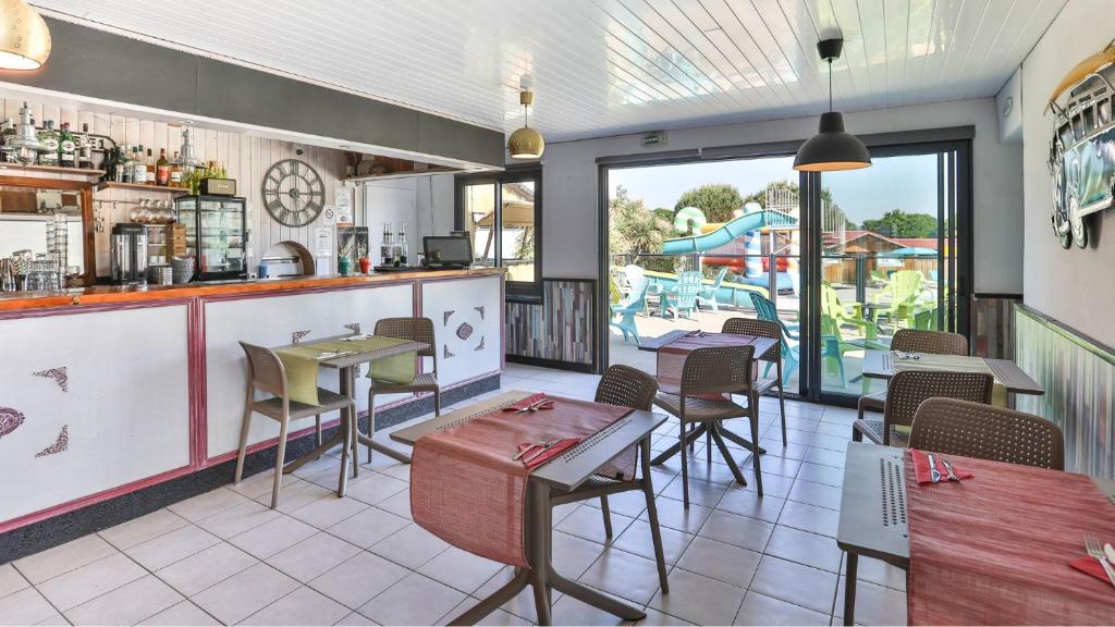 un restaurant avec des tables et des chaises et un bar dans l'établissement Camping Ushuaïa Villages Le Parc de la Grève, à LʼAiguillon-sur-Vie