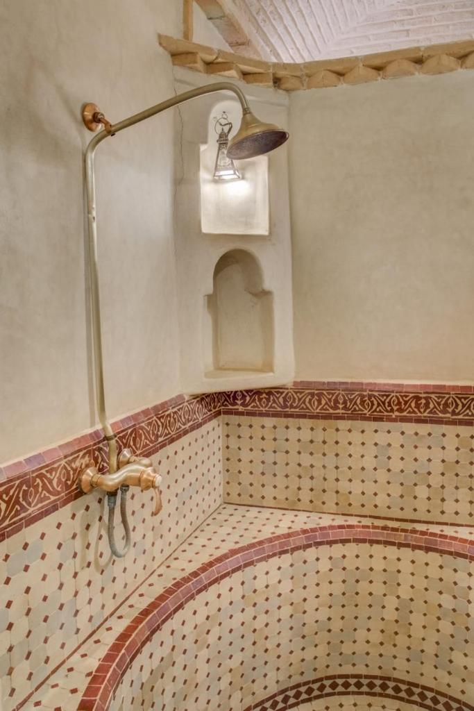 La salle de bains est pourvue d'une douche avec une lumière sur le mur. dans l'établissement Riad Jnane Ines, à Taroudant