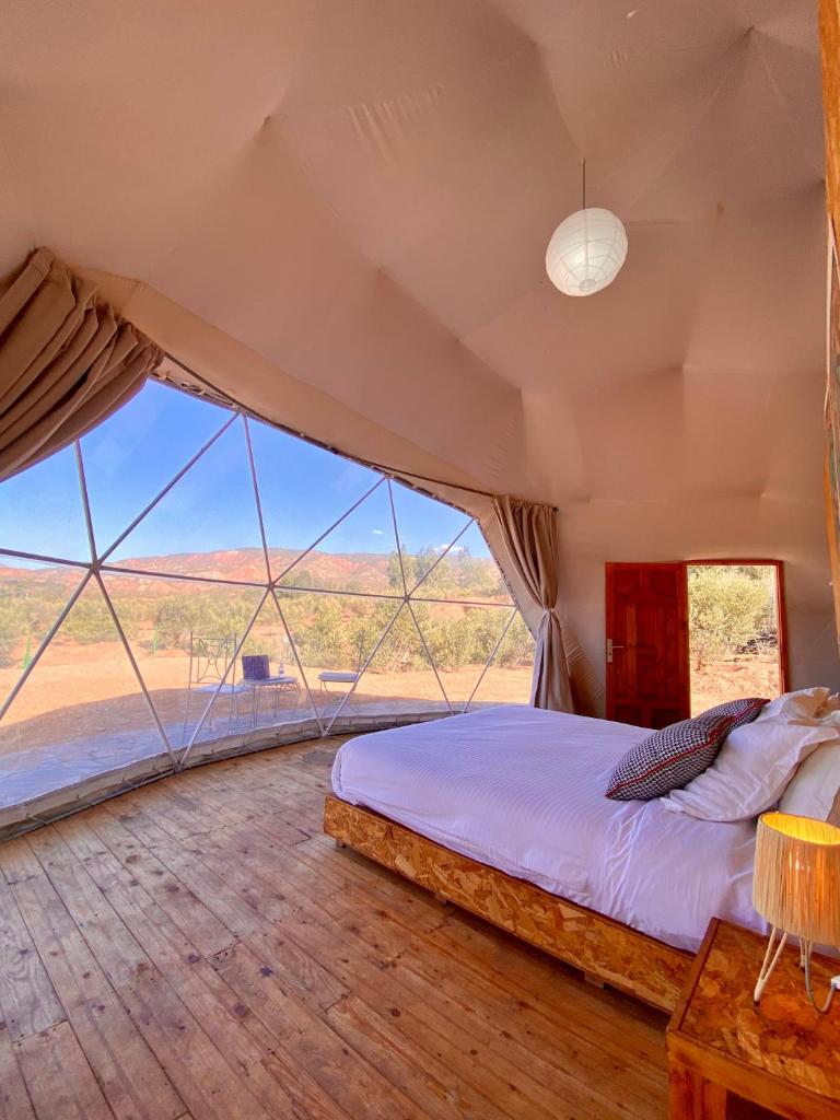 une chambre avec un lit et une grande fenêtre dans l'établissement Ksar Shama, à Ouirgane