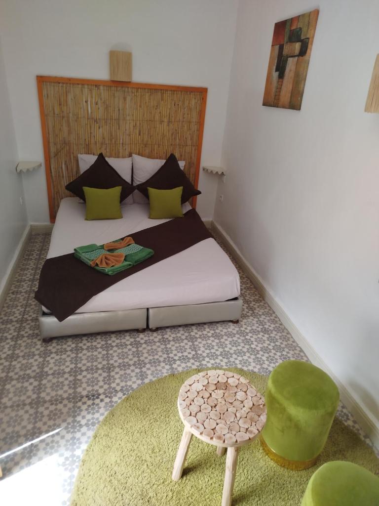 - une chambre avec un lit et un tabouret vert dans l'établissement Riad Bab Lakhmiss, à Marrakech