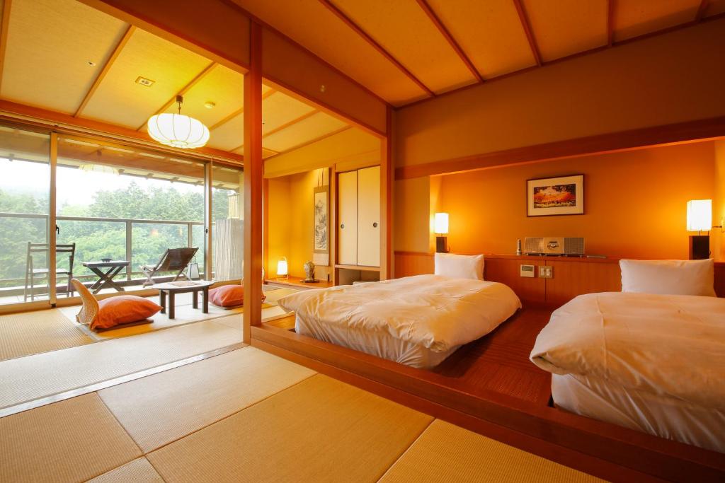 une chambre avec deux lits et un grand miroir dans l'établissement Yumenoian Yuyake Koyake, à Himeji