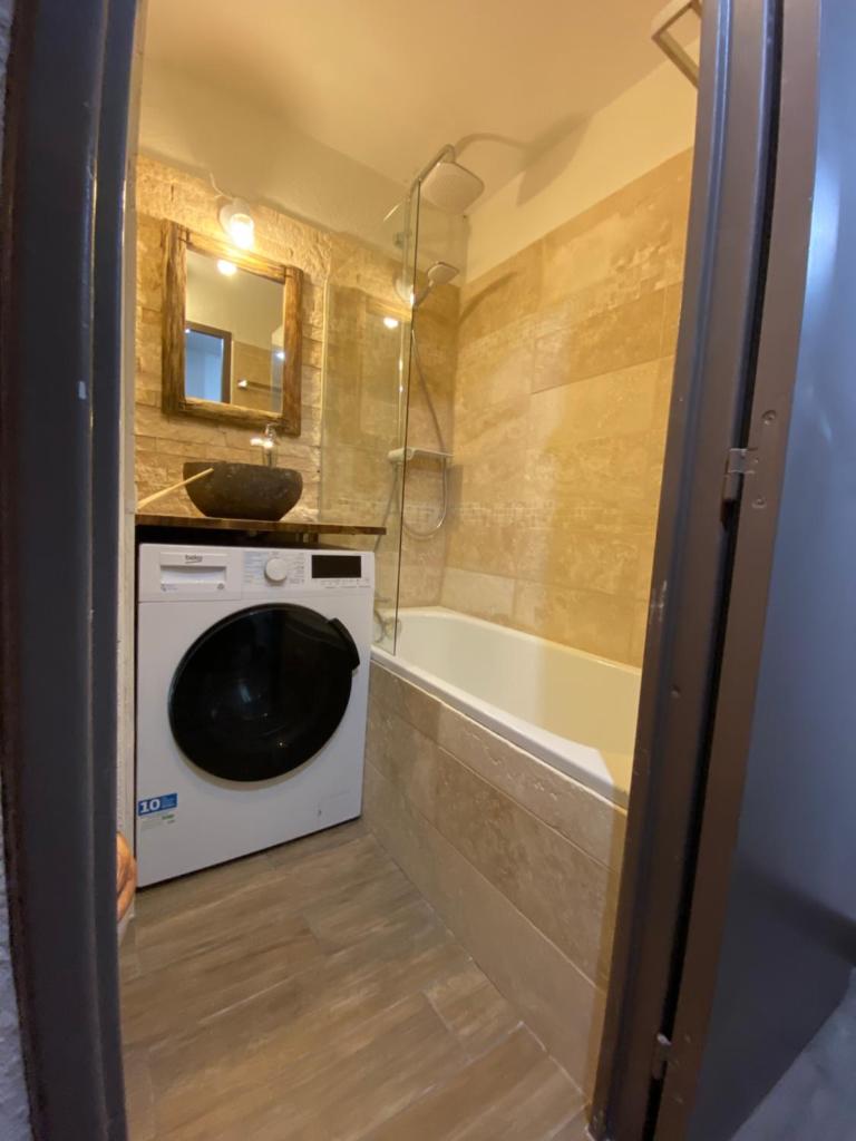 une salle de bain avec un lave-linge et une baignoire dans l'établissement Antarès Location Avoriaz, à Avoriaz