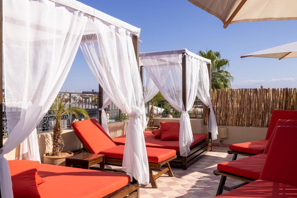 d'une terrasse avec des chaises rouges et des rideaux blancs. dans l'établissement Riad Laz Mouassine & Wellness, à Marrakech