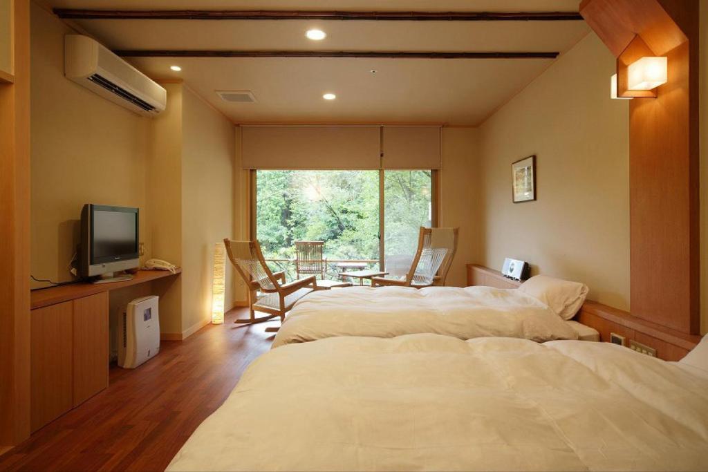 Cette chambre comprend 3 lits, une télévision et une table. dans l'établissement Yumenoian Yuyake Koyake, à Himeji
