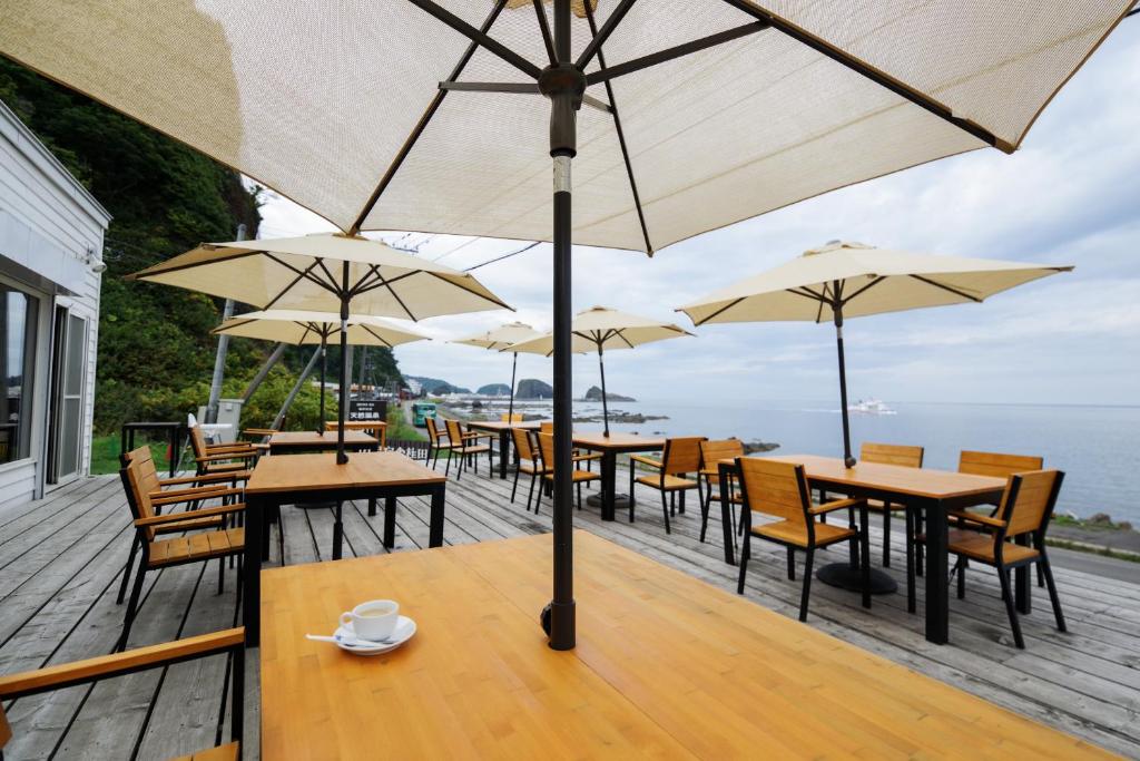 une rangée de tables et de chaises avec parasols sur une terrasse dans l'établissement SHIRETOKO Kokun Kekun, à Shari