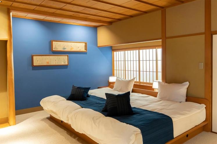 - un grand lit dans une chambre dotée d'un mur bleu dans l'établissement Asadaya, à Kanazawa