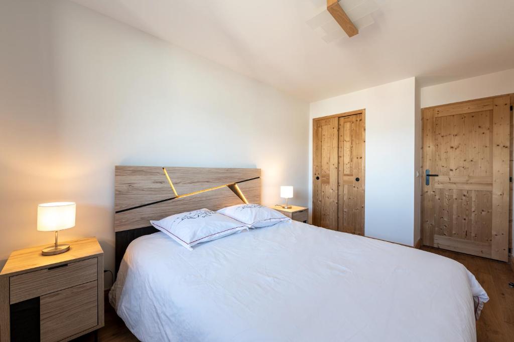 une chambre avec un grand lit blanc et du parquet dans l'établissement L'écrin des sapins, à Aime La Plagne
