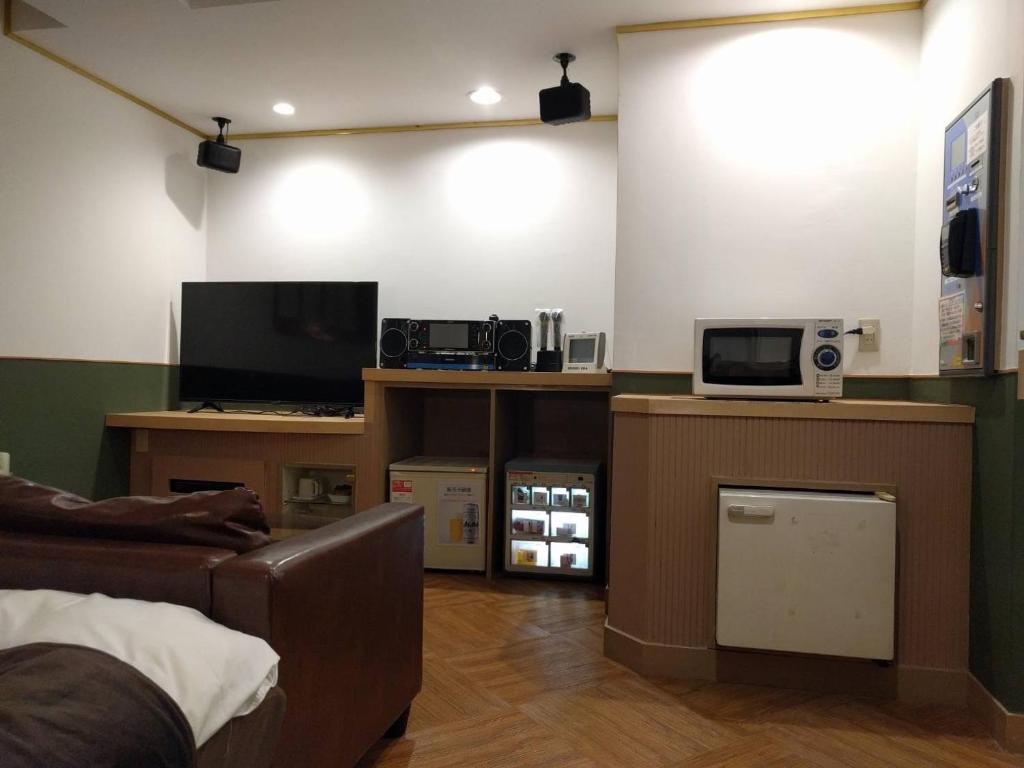 un salon avec un canapé et une télévision dans l'établissement ホテルロコズマウイ, à Honjo