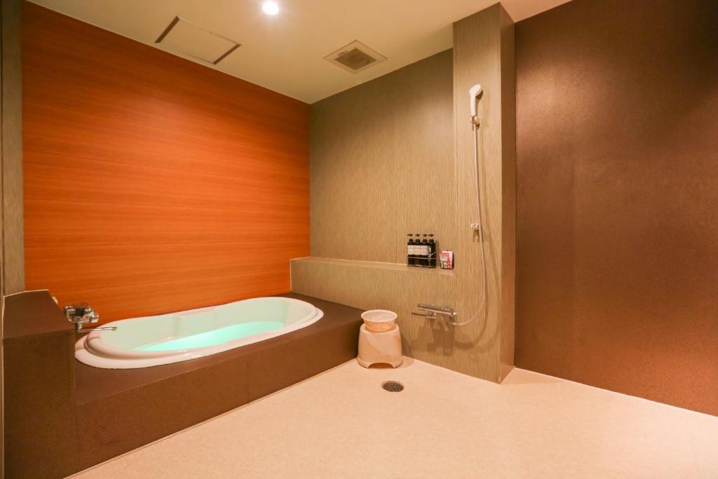 une salle de bain avec baignoire et douche dans l'établissement ホテルロコズマウイ, à Honjo
