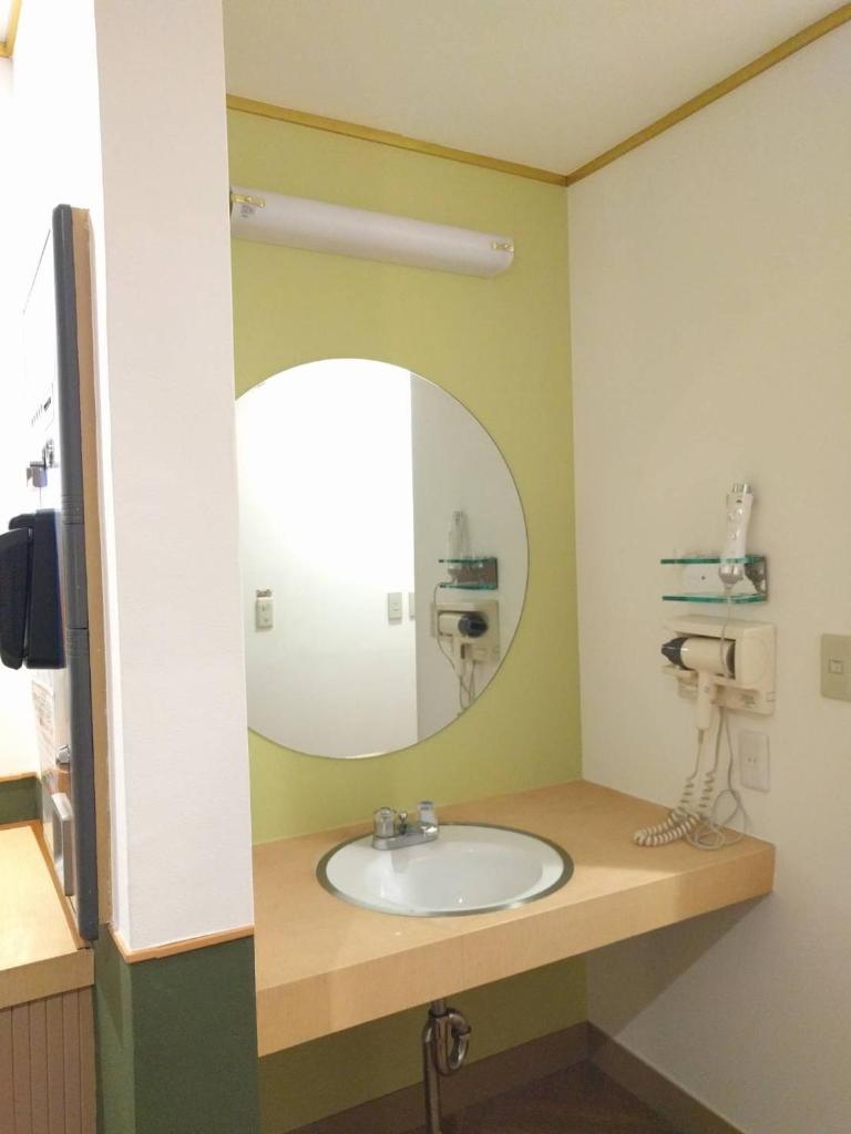 une salle de bain avec un lavabo et un miroir dans l'établissement ホテルロコズマウイ, à Honjo 7 autres photos