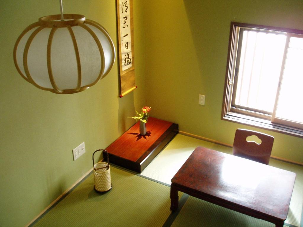 une salle à manger avec une table, une chaise et un lustre dans l'établissement Inn Kawashima, à Kyoto