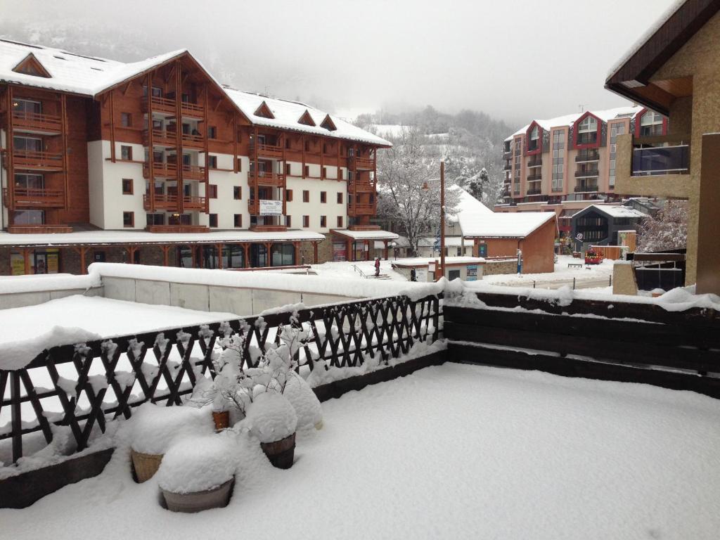 un balcon couvert de neige avec des bâtiments en arrière-plan dans l'établissement T3 avec terrasse plein sud au pied des télécabines, à Briançon