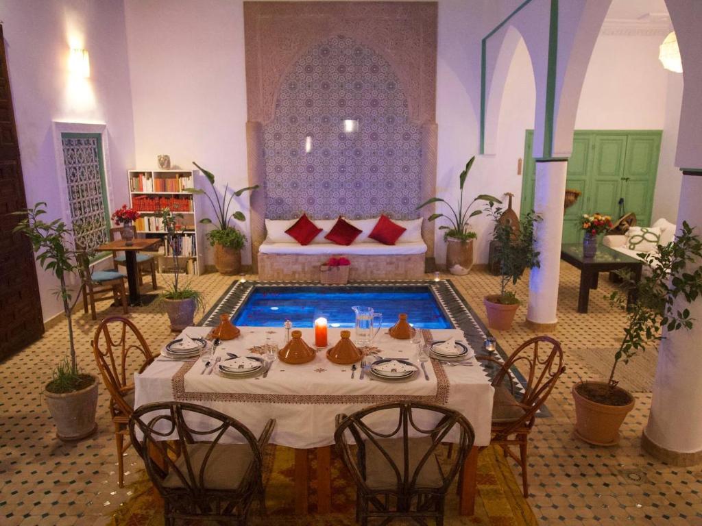 une salle à manger avec une table et une piscine dans l'établissement Riad Ocallaghan, à Marrakech