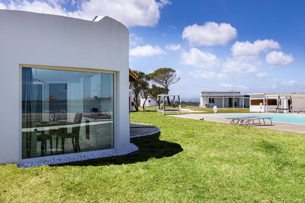 une maison blanche sur l'herbe à côté d'une piscine dans l'établissement Baia del Sole Resort, à Olbia