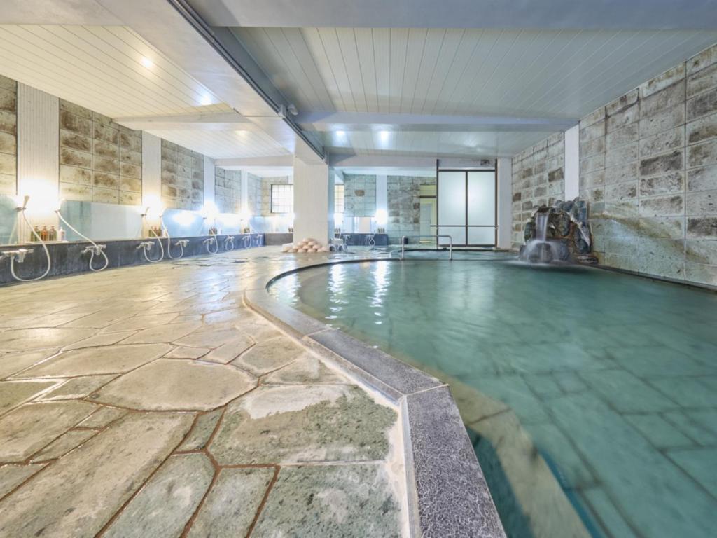 - une piscine dans une chambre dotée d'un mur en pierre dans l'établissement Shuzenji Onsen Hotel Takitei, à Izu