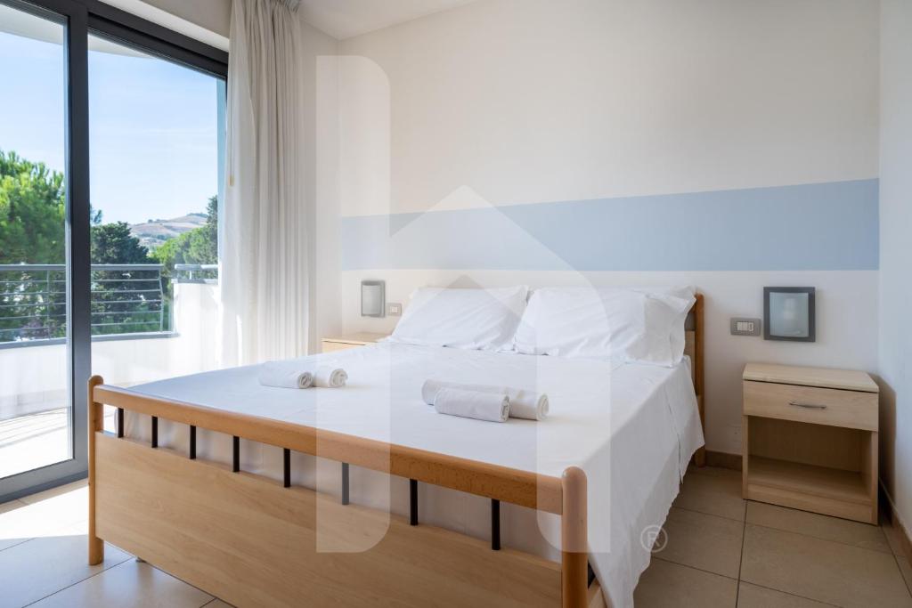 une chambre avec un lit blanc avec une grande fenêtre dans l'établissement Homiday - Holiday Rendez Vous, à Pineto