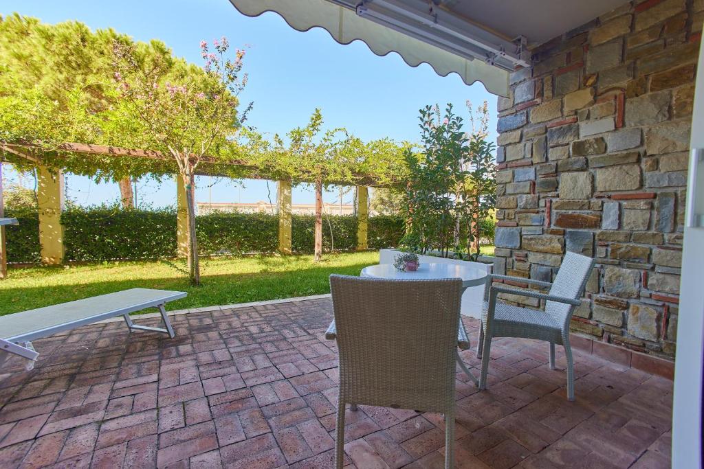 un patio avec une table et des chaises et un mur en pierre dans l'établissement Ancora Resort, à Acciaroli