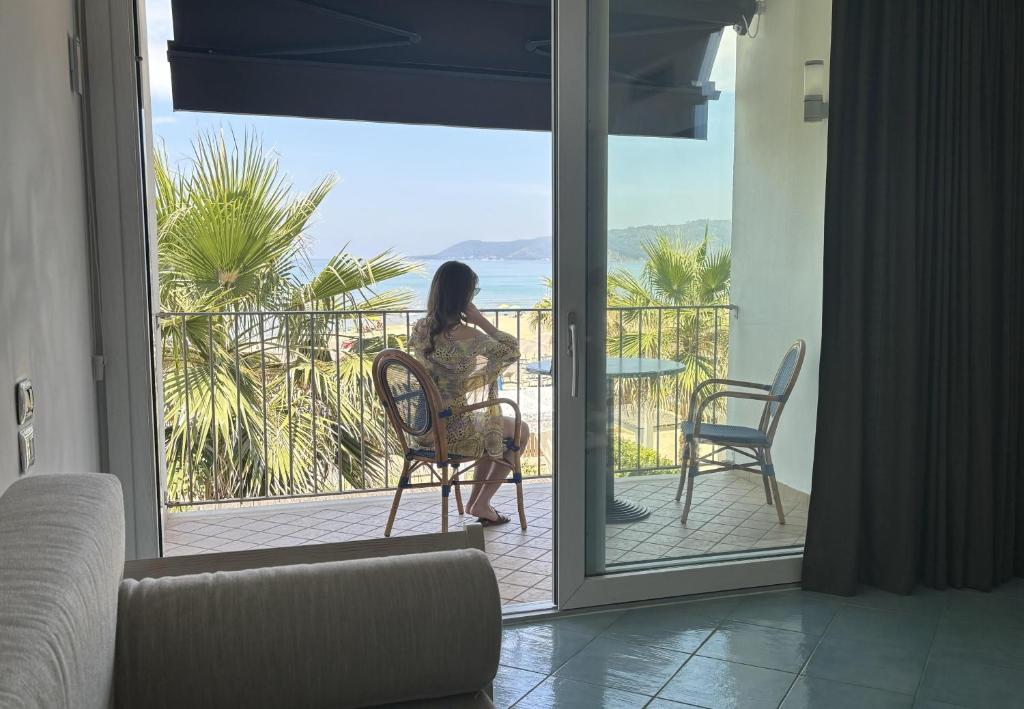 une femme assise sur une chaise sur un balcon donnant sur l'océan dans l'établissement Ancora Resort, à Acciaroli