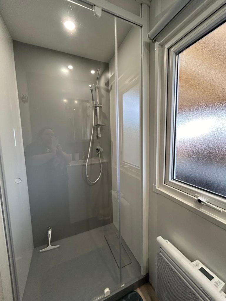 une douche avec une porte vitrée dans une salle de bain dans l'établissement Le Paradis du Rhône - mobilhome moderne et confortable, à Condrieu