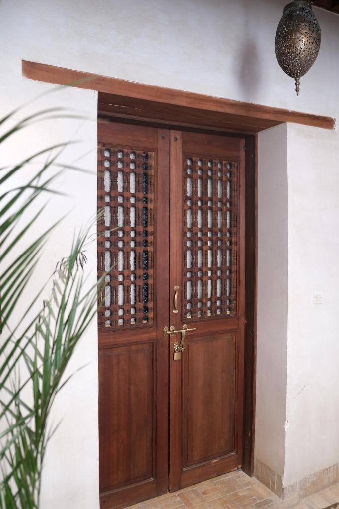 une porte en bois dans un mur blanc avec une plante dans l'établissement Dar Rafti, à Fès