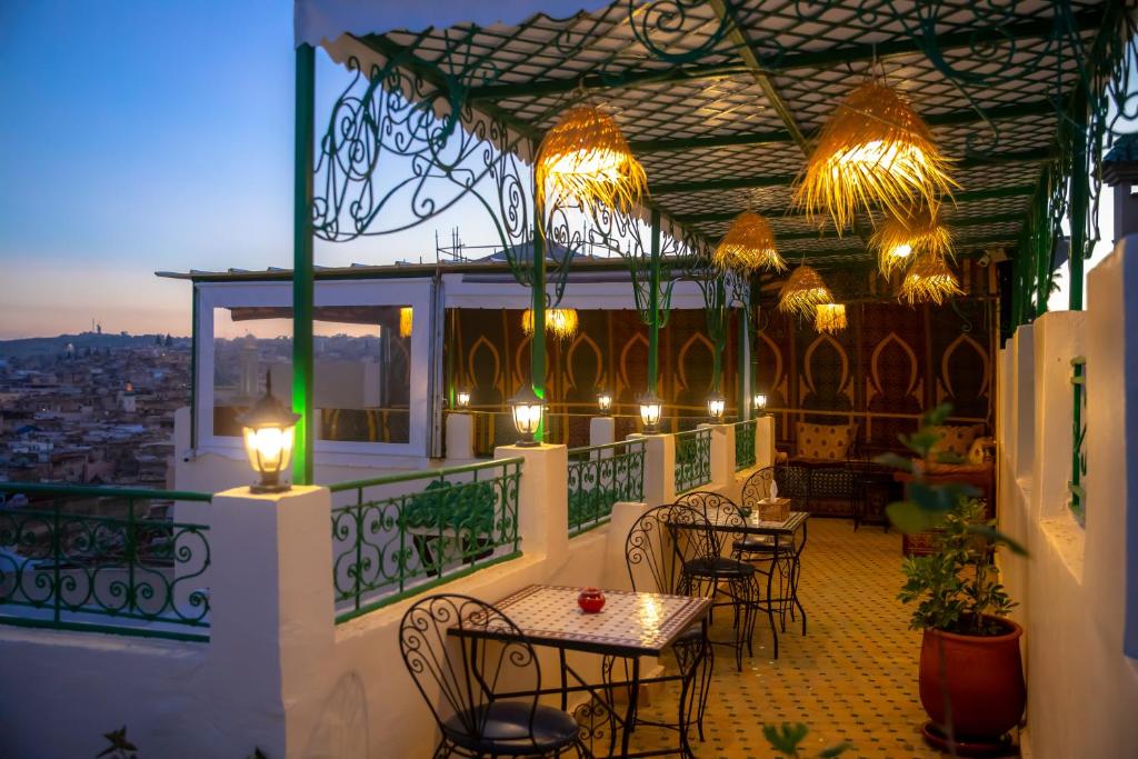 d'une terrasse avec des tables et des chaises sur un balcon éclairé. dans l'établissement Riad Bahja Fez, à Fès