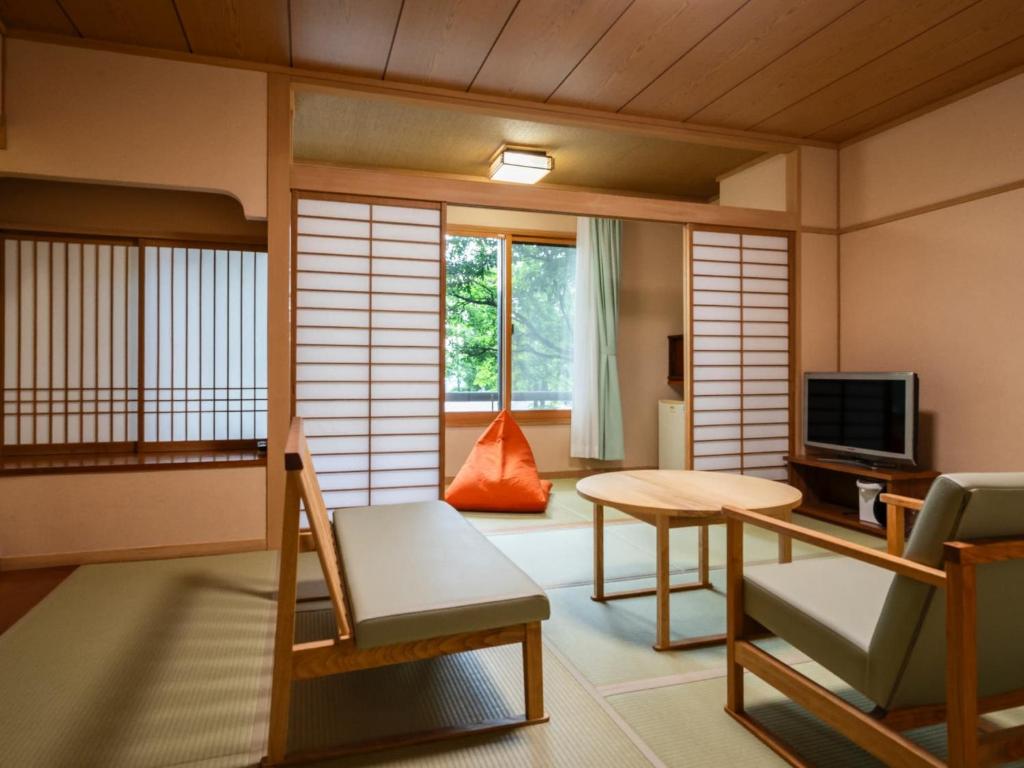 Cette chambre japonaise comprend un lit et une télévision. dans l'établissement Hibikino, à Shibukawa