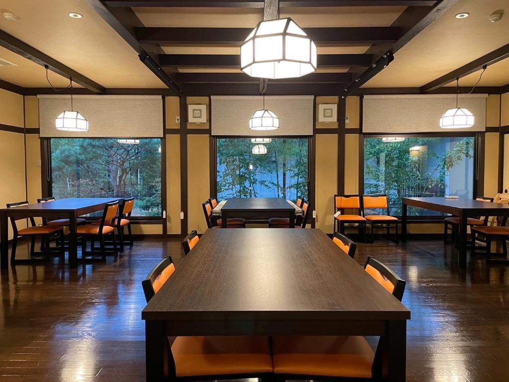 une salle à manger avec tables, chaises et fenêtres dans l'établissement 旅庵 川喜, à Omachi