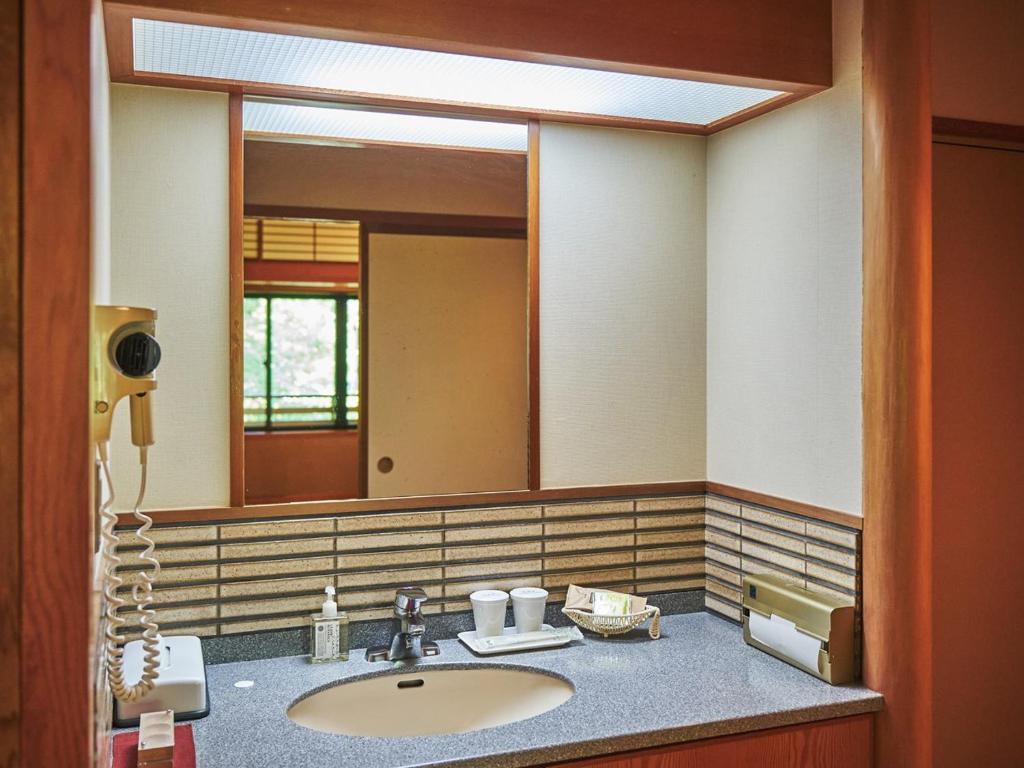 une salle de bain avec un lavabo et un grand miroir dans l'établissement Oyado Nagomino, à Azumino