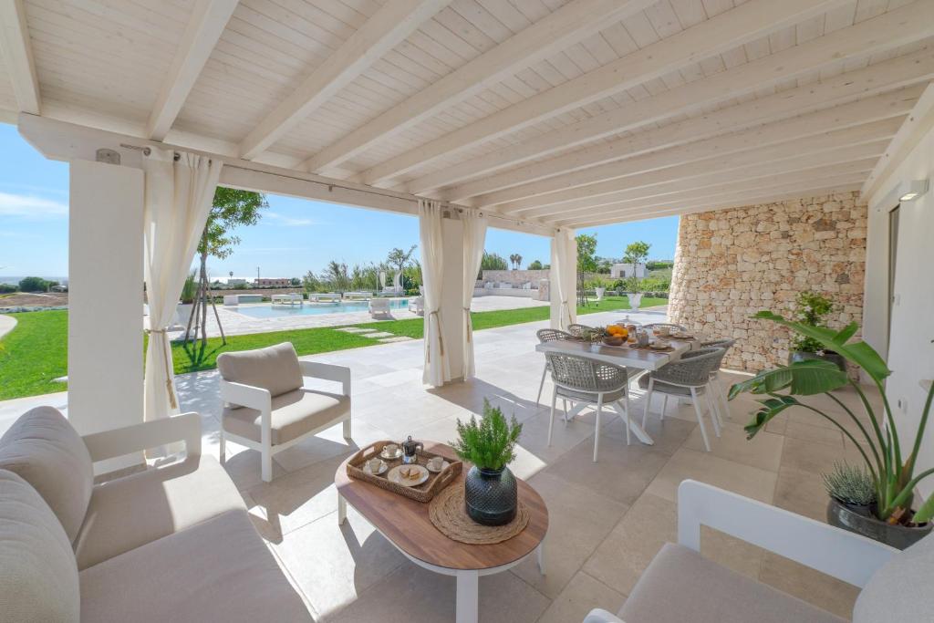 un patio avec une table et des chaises et une piscine dans l'établissement VILLA FLORI', à Marina di Pescoluse