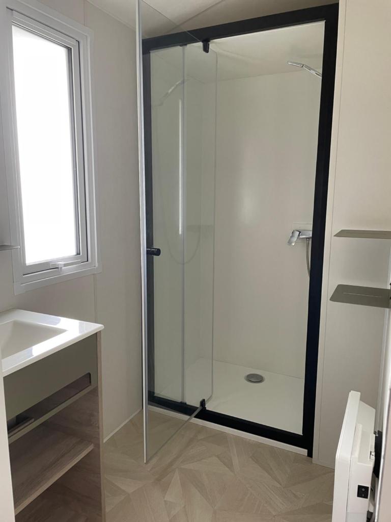une salle de bain avec une douche en verre et un lavabo dans l'établissement Mobilhome, à Biscarrosse
