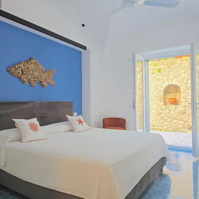 une chambre avec un grand lit blanc et une fenêtre dans l'établissement Casa Infinito, à Capri