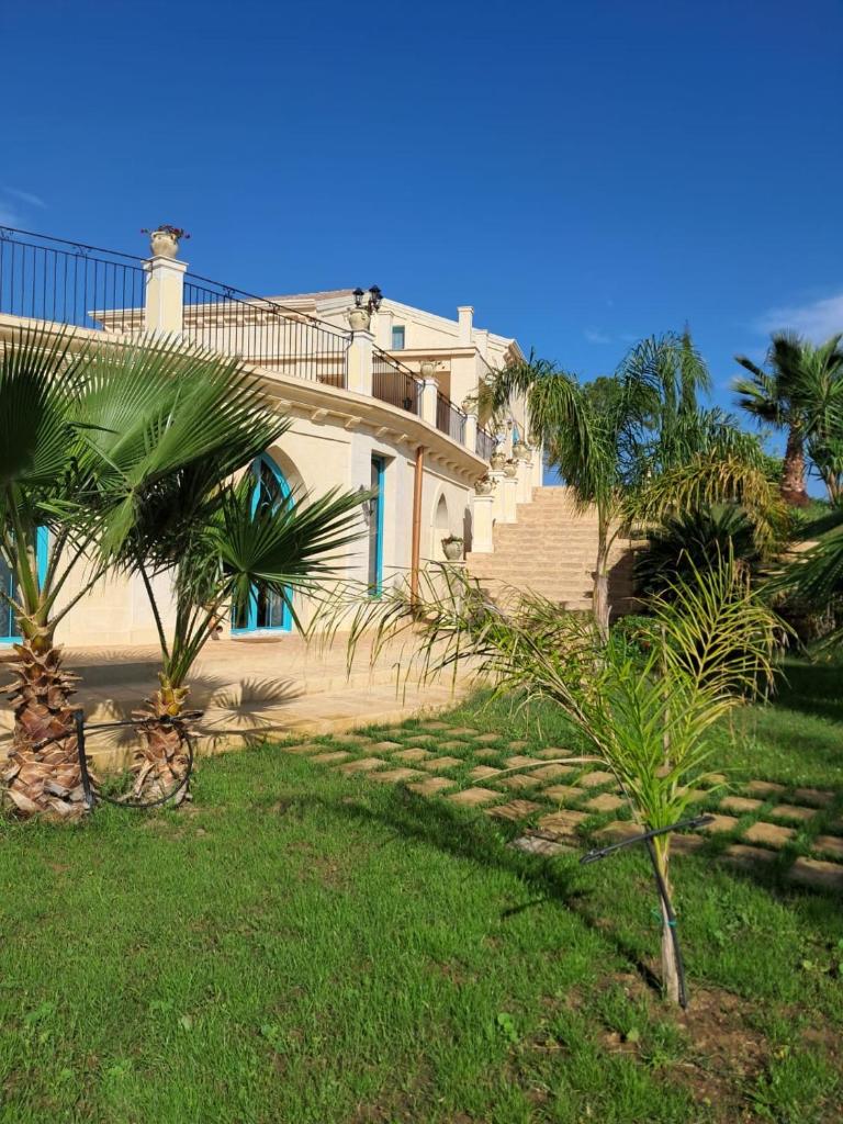 une maison avec un escalier et des palmiers dans l'herbe dans l'établissement Villa Brikinnia, à Lentini