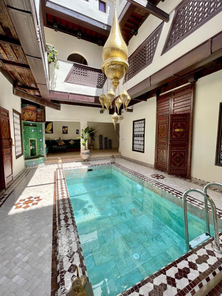 - une piscine avec un lustre dans un bâtiment dans l'établissement Riad Jolie, à Marrakech