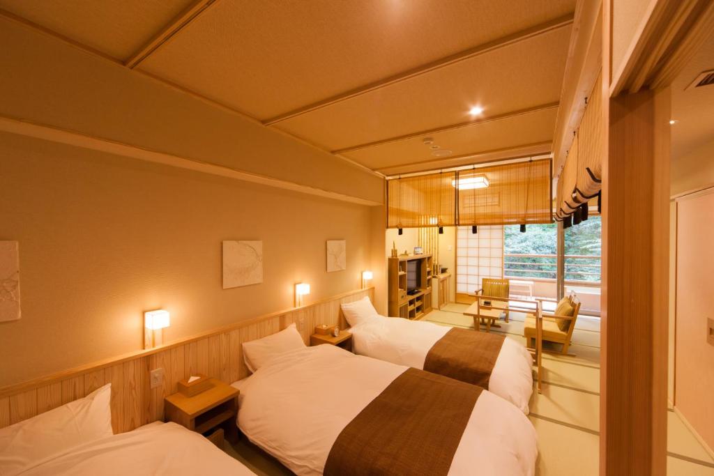 une chambre d'hôtel avec trois lits et une fenêtre dans l'établissement Ikyu, à Ise