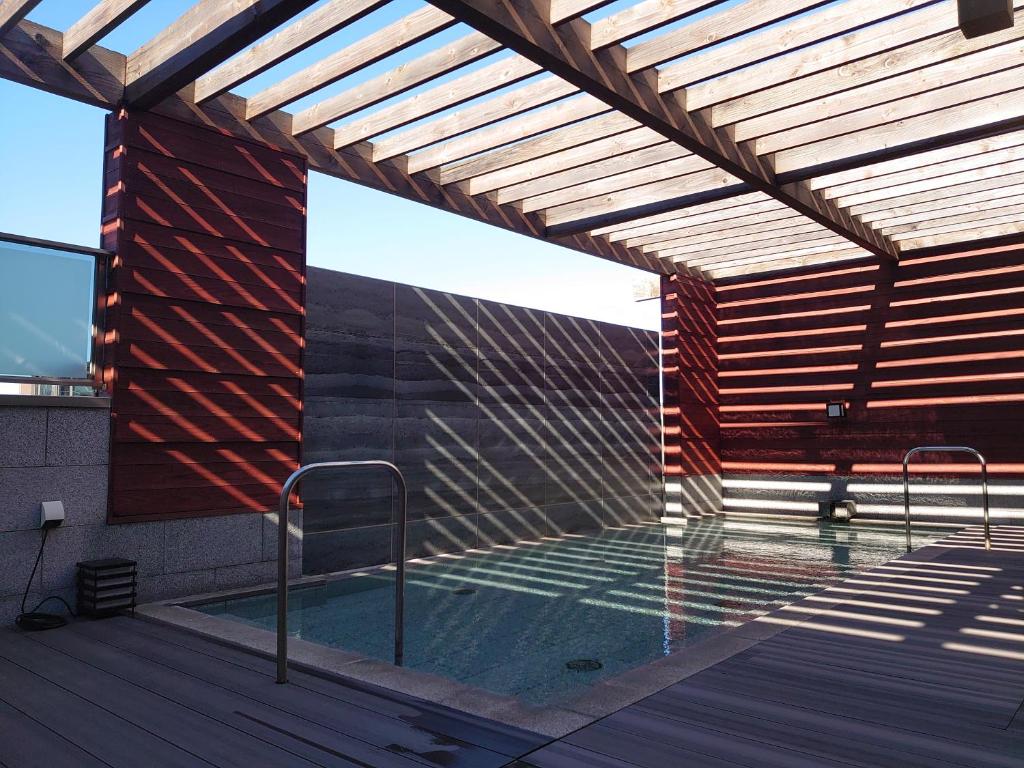 - un bâtiment avec une piscine et une pergola en bois dans l'établissement Tokigasane, à Kaga